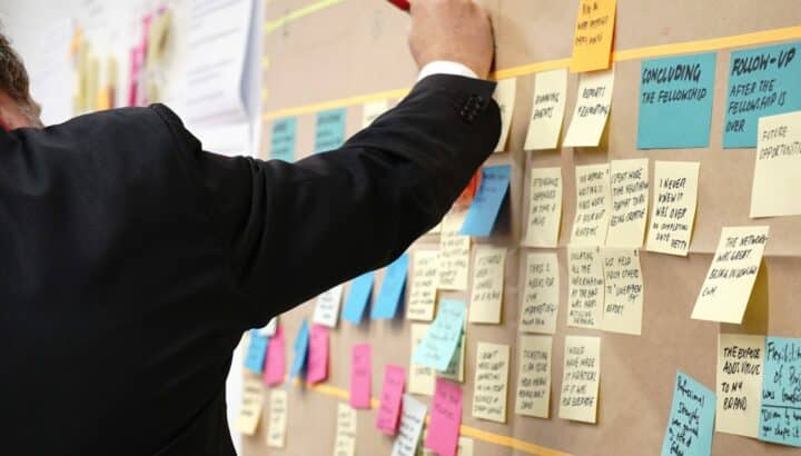 Homme en costume disposant des post-it colorés sur un tableau mural
