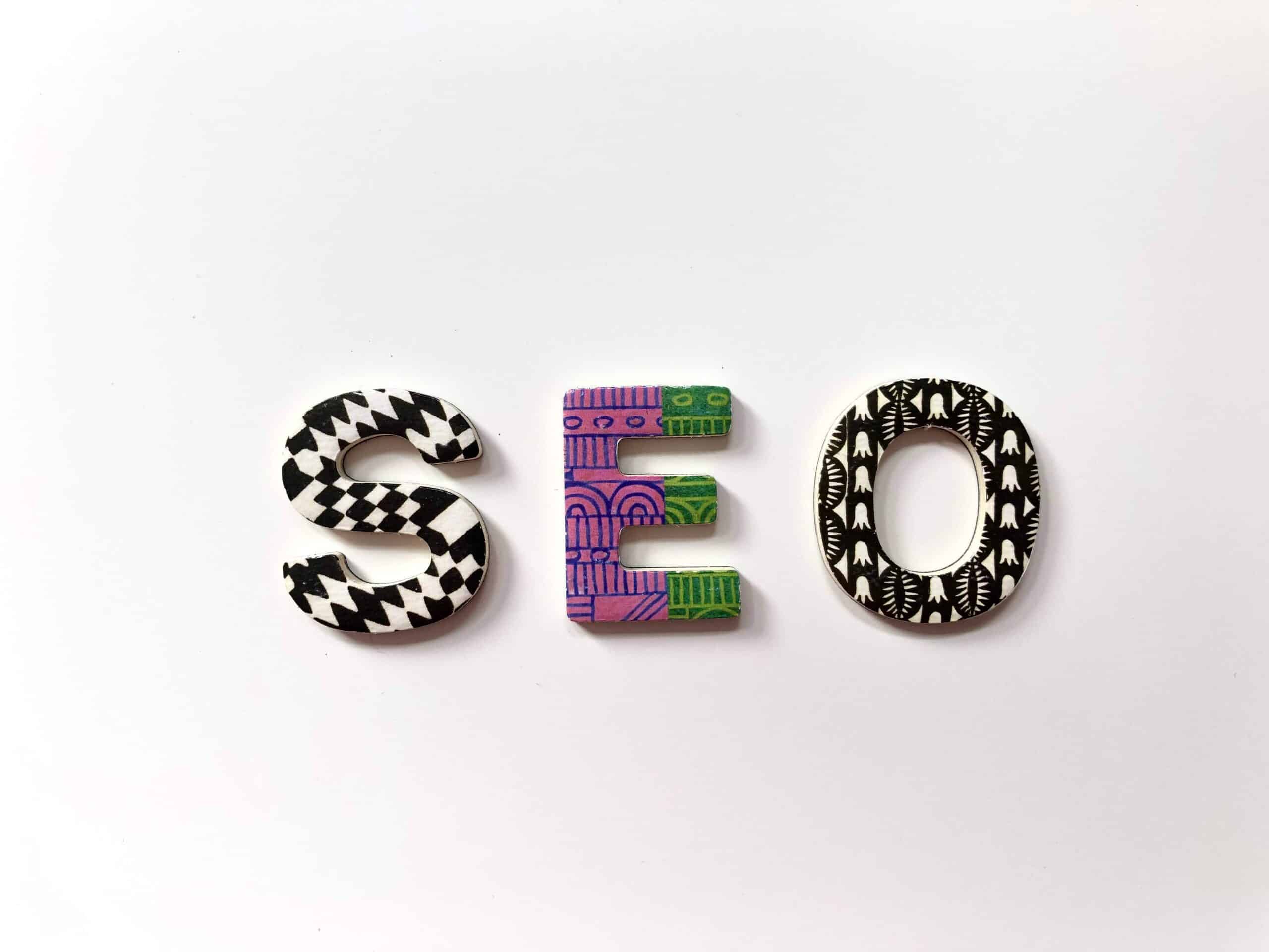 Lettres en bois à motifs colorés formant le mot "SEO"
