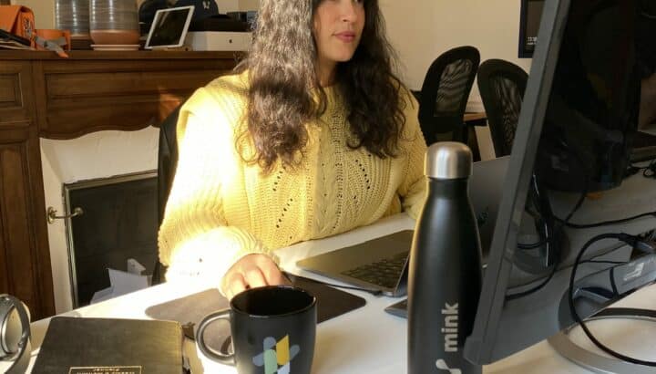Femme travaillant à son bureau avec gourde et mug Mink, intérieur lumineux
