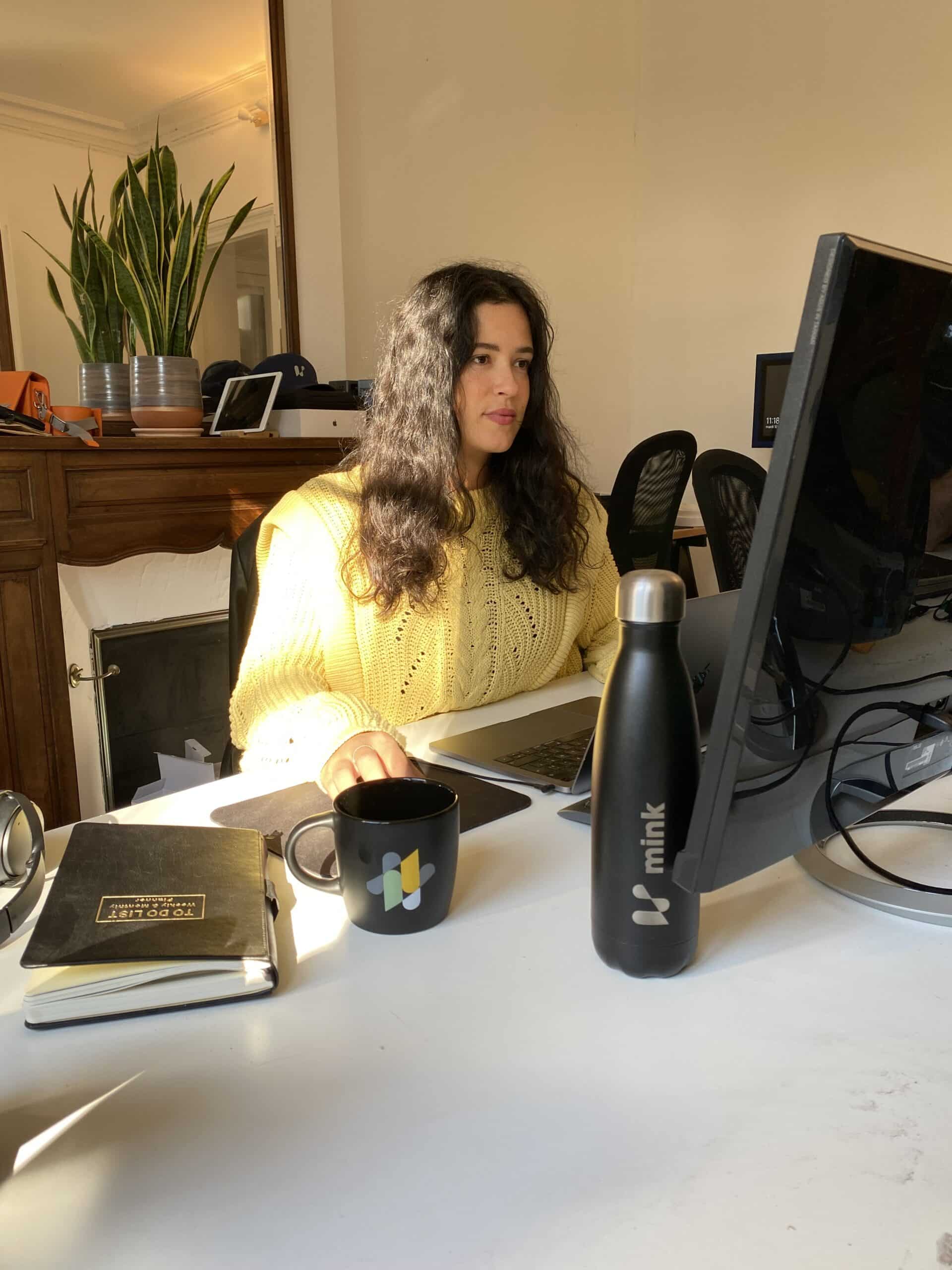 Femme travaillant à son bureau avec gourde et mug Mink, intérieur lumineux