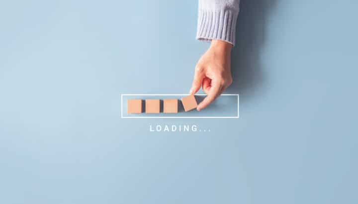 Main plaçant des cubes en bois dans une barre de progression avec le texte "Loading..."