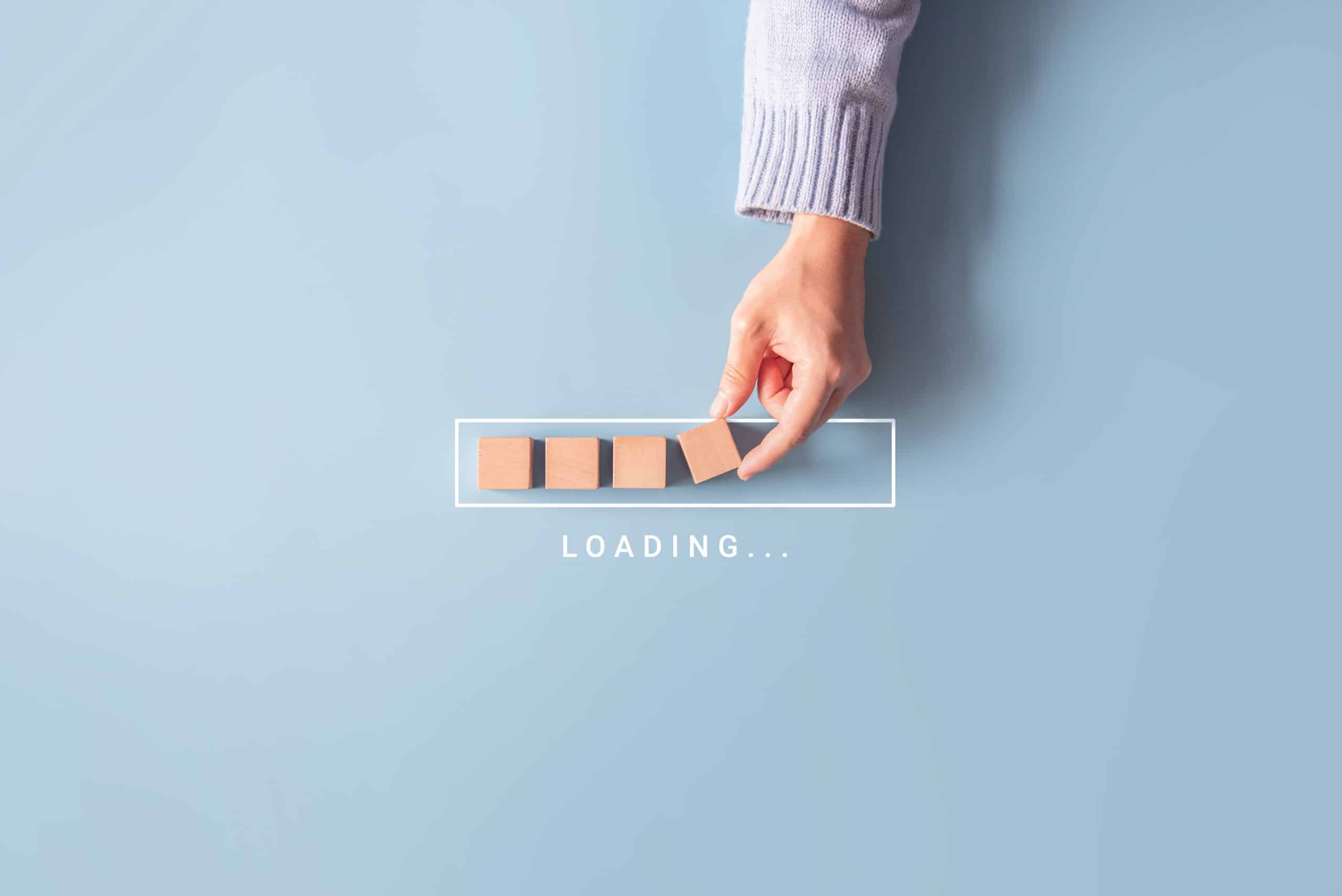 Main plaçant des cubes en bois dans une barre de progression avec le texte "Loading..."
