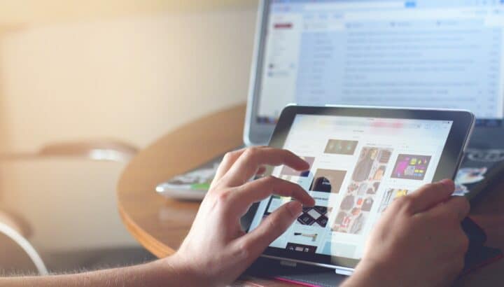 Personne touchant l'écran d'une tablette affichant un site e-commerce