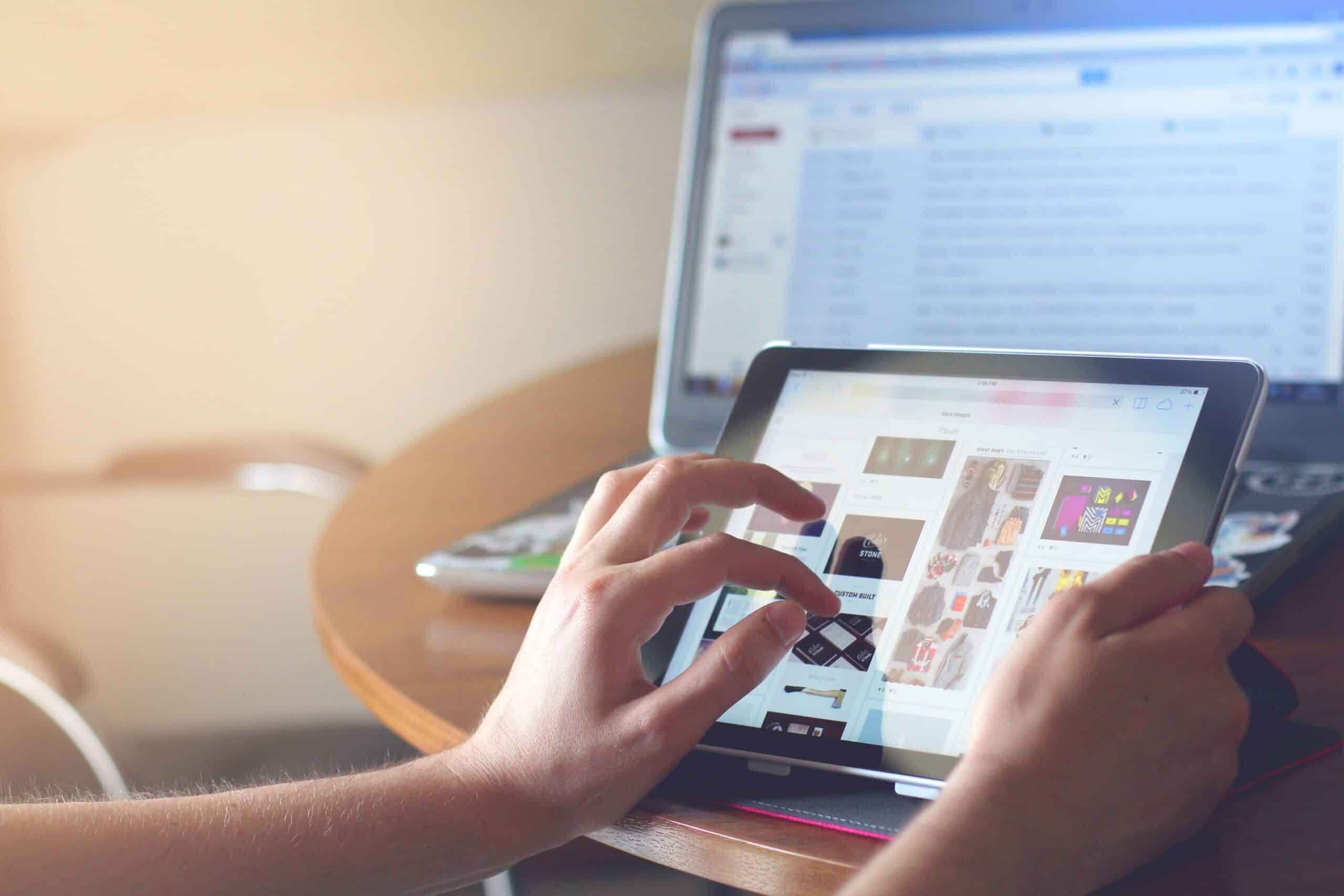 Personne touchant l'écran d'une tablette affichant un site e-commerce