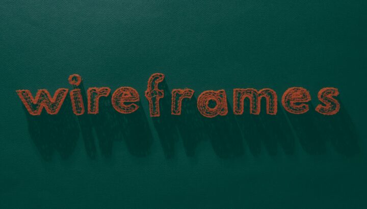 Mot "wireframes" brodé en orange sur un fond de tissu vert texturé