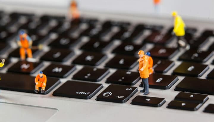 Petites figurines d'ouvriers en tenue orange posées sur les touches d'un clavier