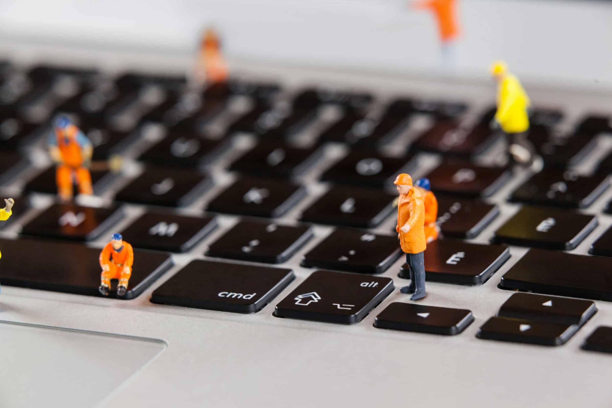 Petites figurines d'ouvriers en tenue orange posées sur les touches d'un clavier