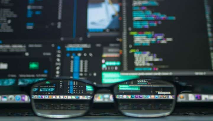 Paire de lunettes posée devant un écran affichant du code