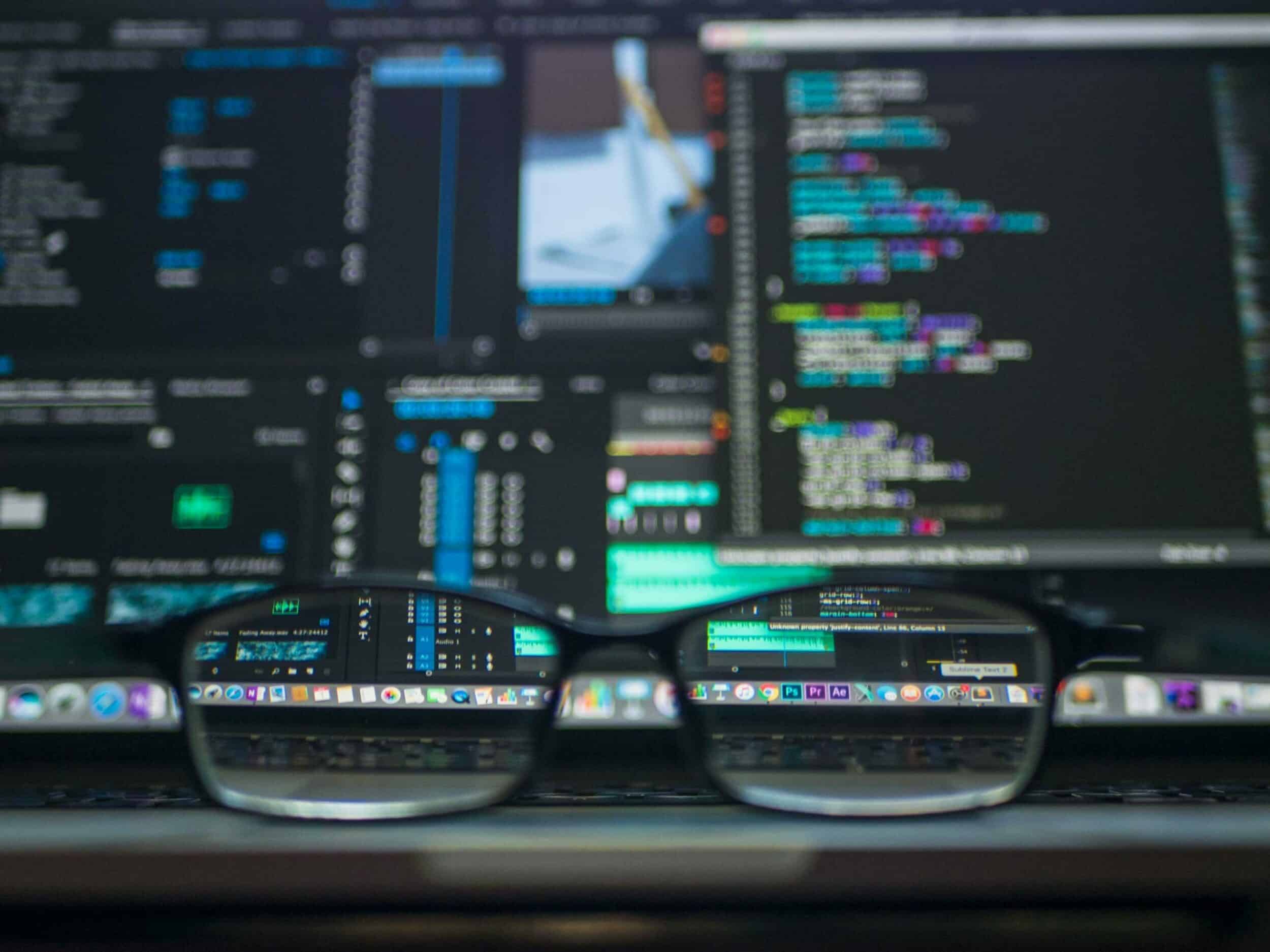 Paire de lunettes posée devant un écran affichant du code