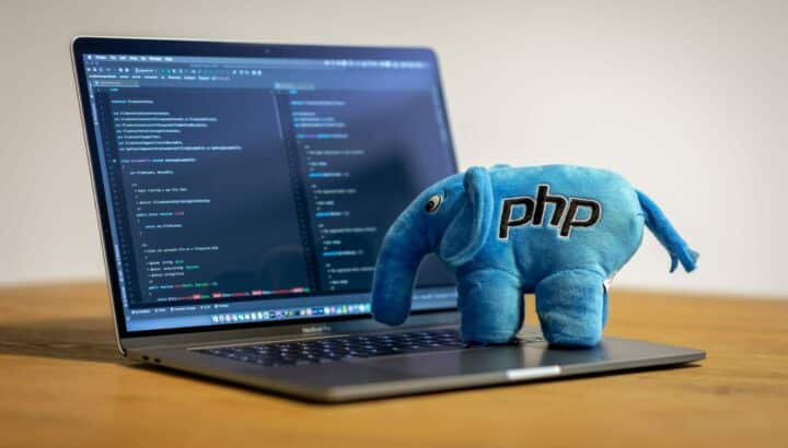 Peluche éléphant bleu logo PHP posée sur un clavier affichant du code