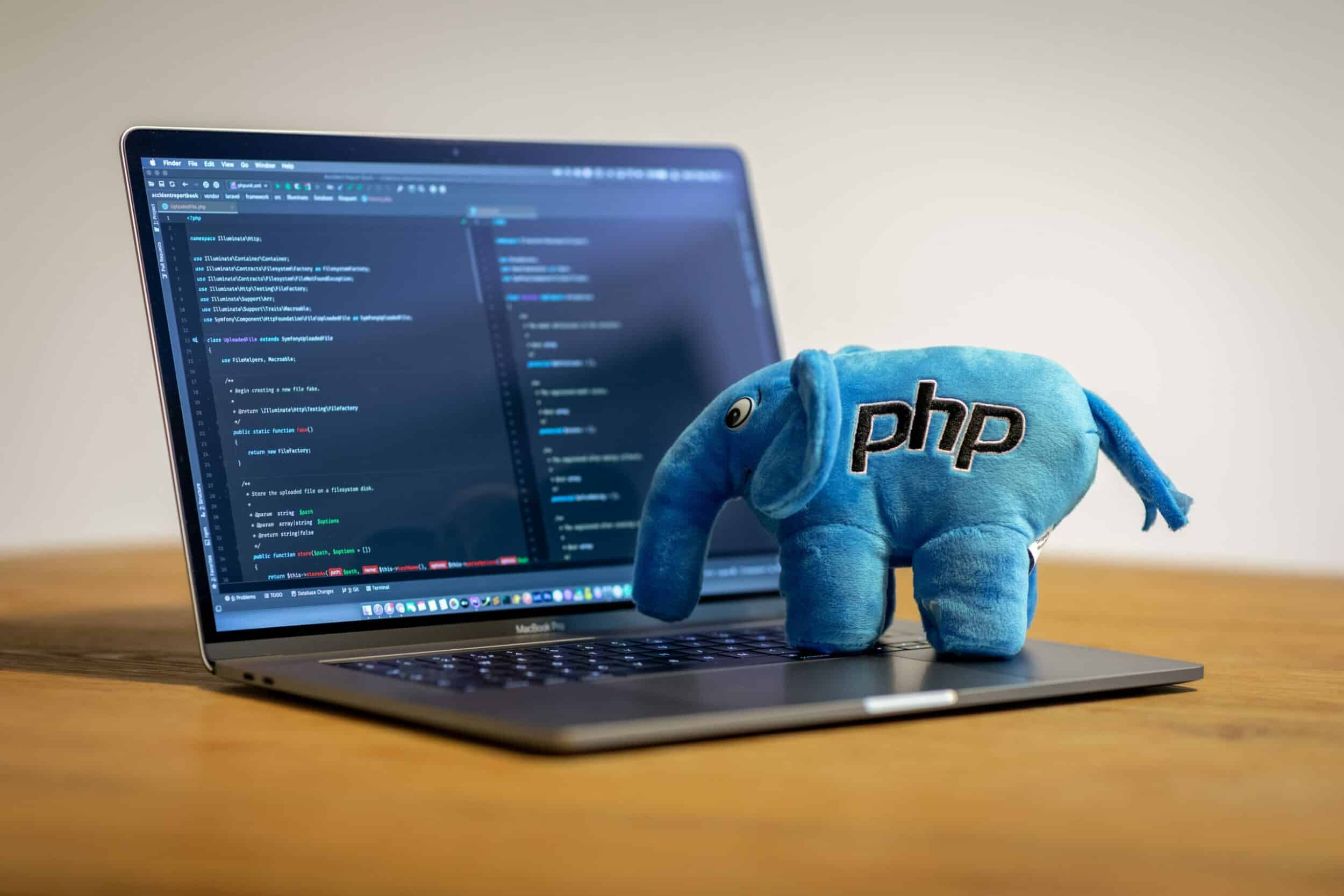 Peluche éléphant bleu logo PHP posée sur un clavier affichant du code