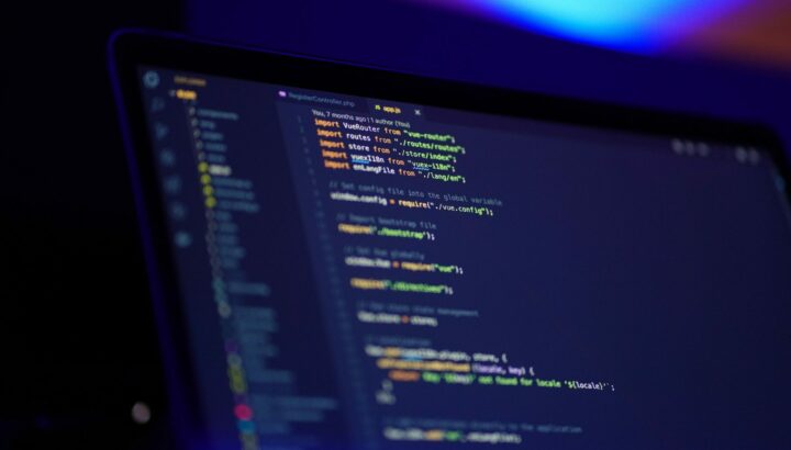 Écran de laptop affichant du code Vue.js, éclairage bokeh coloré en arrière-plan