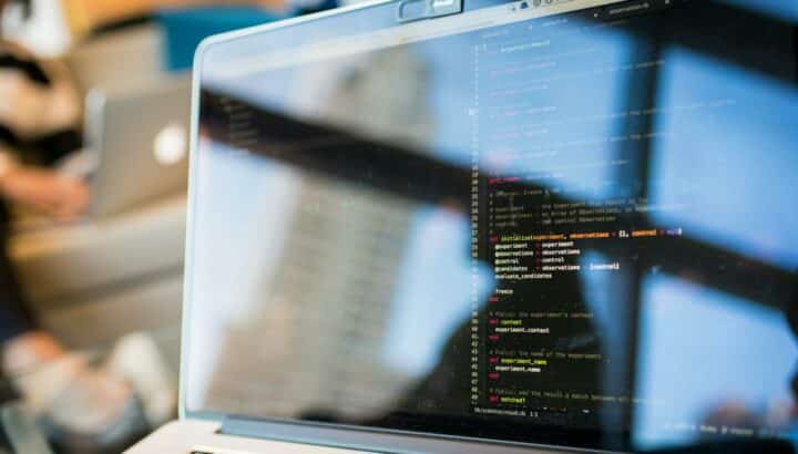 Écran de laptop affichant du code Ruby, reflet du bureau visible sur l'écran