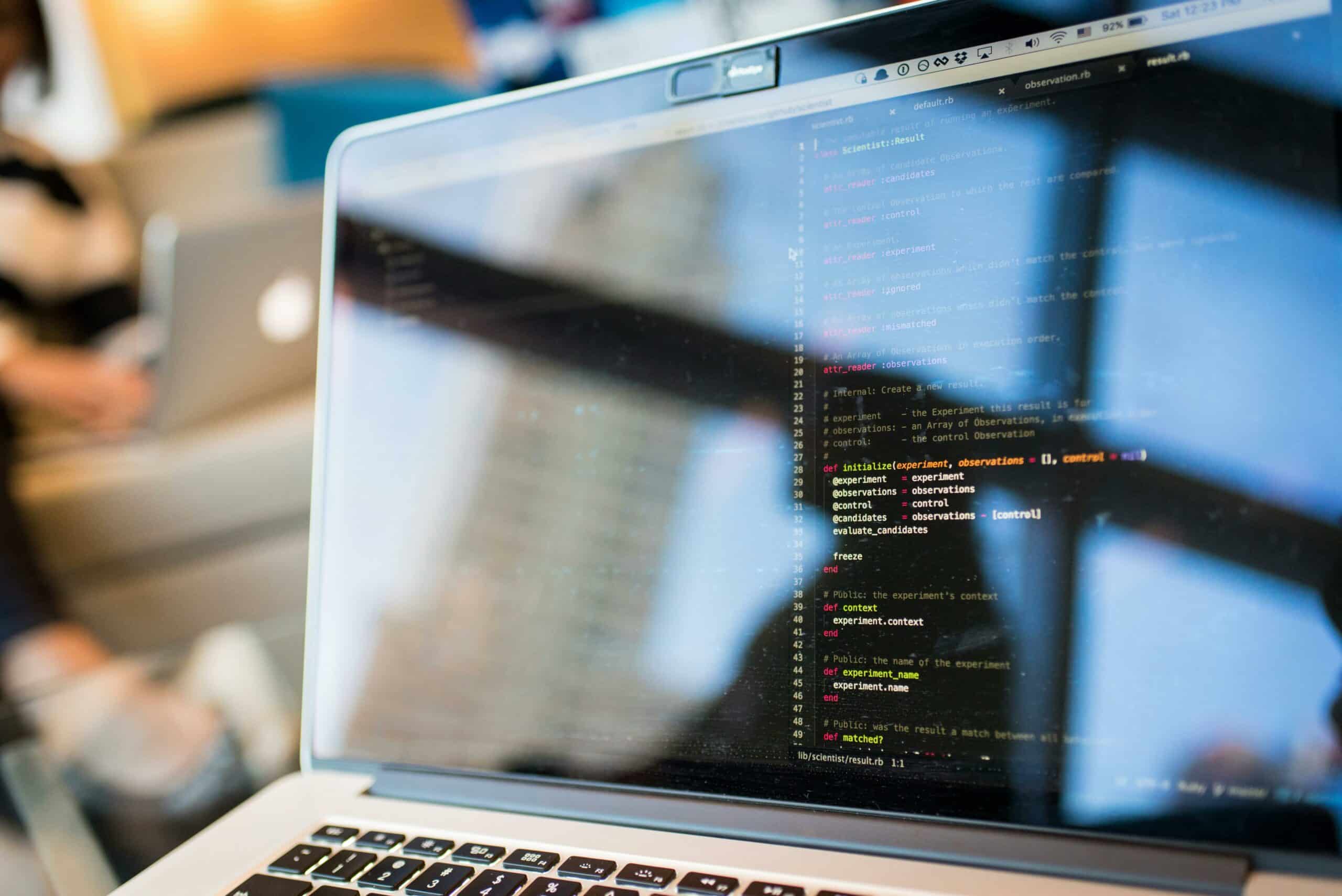 Écran de laptop affichant du code Ruby, reflet du bureau visible sur l'écran