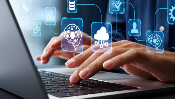 Mains tapant sur un clavier d'ordinateur portable avec icônes IA, cloud et données en surimpression