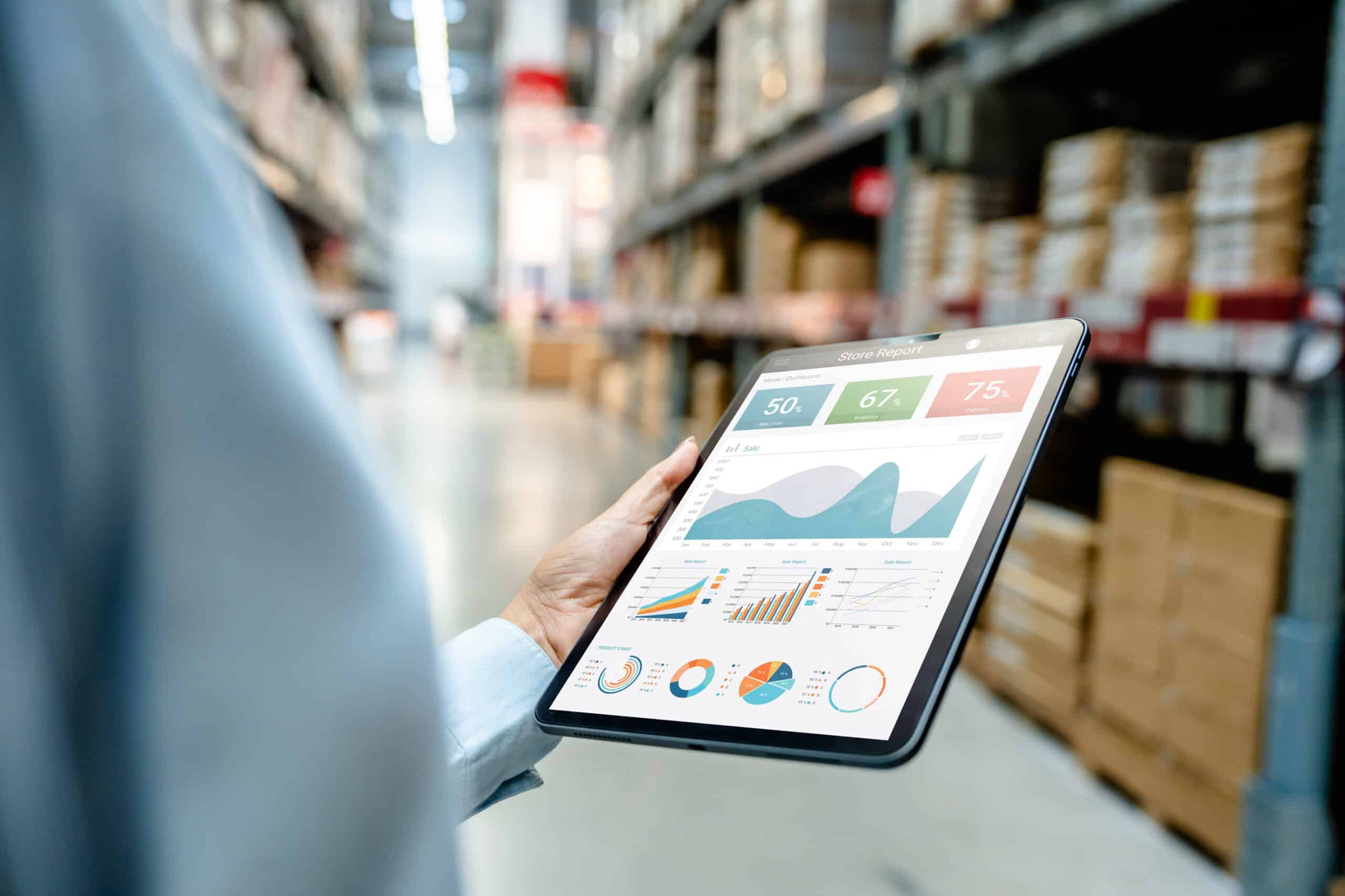 Main tenant une tablette avec graphiques de rapport de magasin, entrepôt logistique en arrière-plan