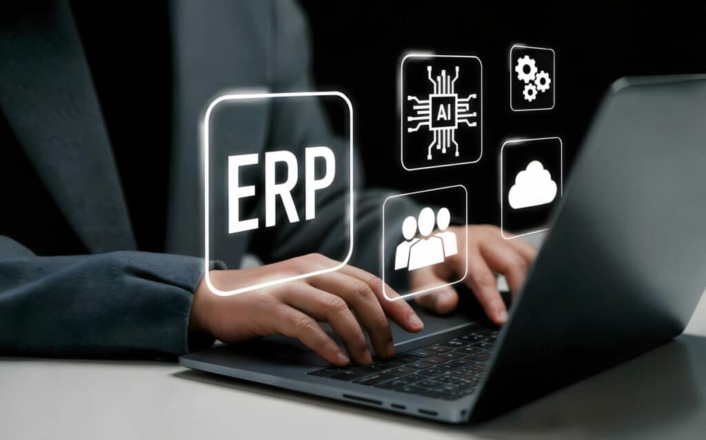 Mains tapant sur un ordinateur portable entourées d'icônes ERP, IA, cloud, équipe et paramètres