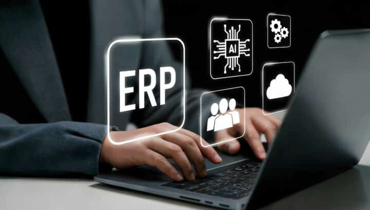 Mains tapant sur un ordinateur portable entourées d'icônes ERP, IA, cloud, équipe et paramètres