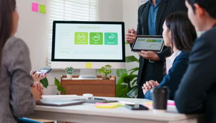 Homme présentant un tableau de bord ESG affichant des indicateurs de gouvernance, environnement et social à trois collègues assis autour d'une table