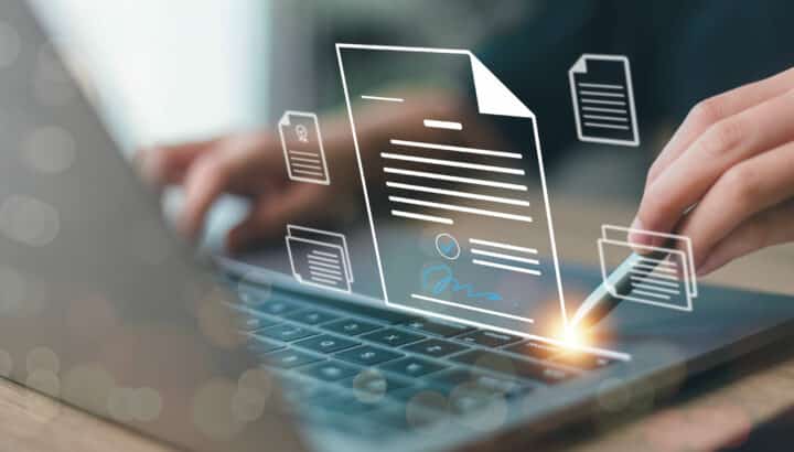 Mains tapant sur un clavier d'ordinateur portable, superposées d'icônes de documents dématérialisés dont un contrat avec signature électronique