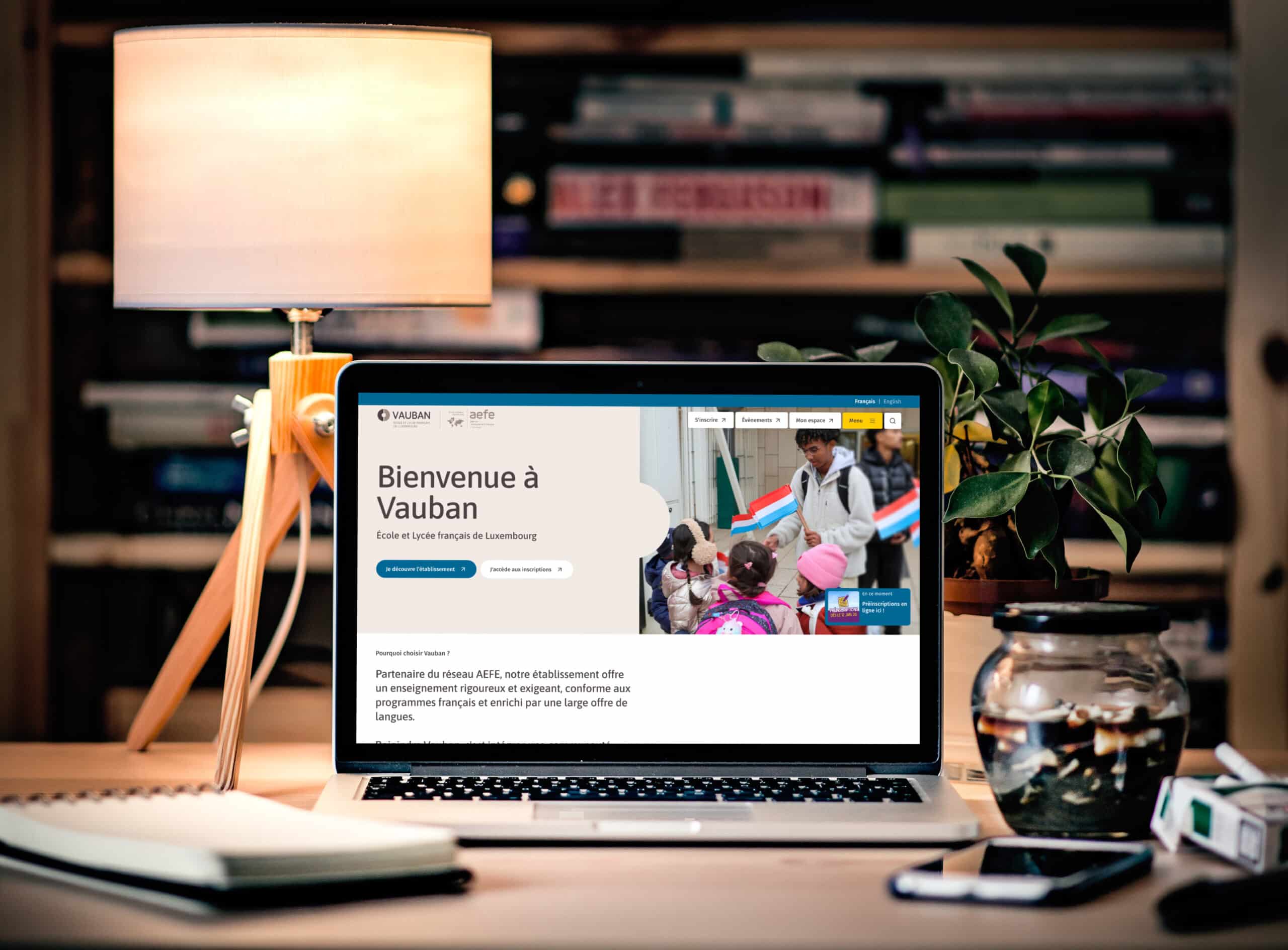 Ordinateur portable affichant le site Vauban sur un bureau avec lampe et plante
