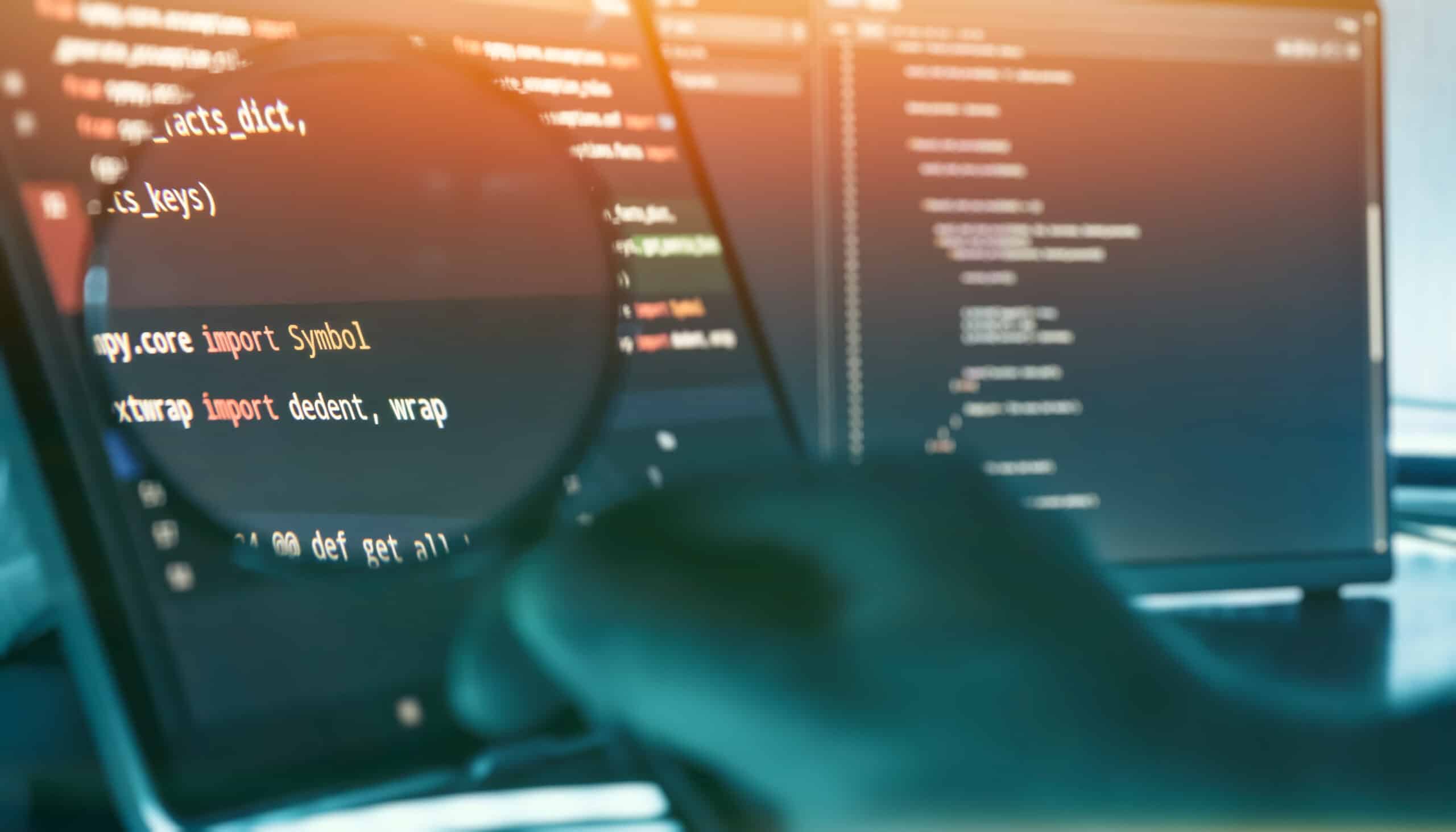 Développeur examinant du code source à la loupe pour un audit de sécurité applicative