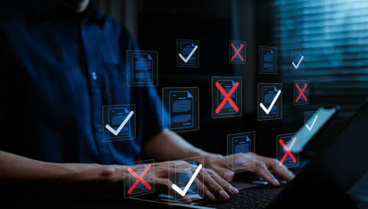 Mains tapant sur un ordinateur portable devant des icônes de documents flottantes marquées de coches vertes et de croix rouges