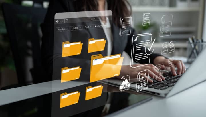 Femme tapant sur un ordinateur portable devant une interface holographique de dossiers et documents numériques